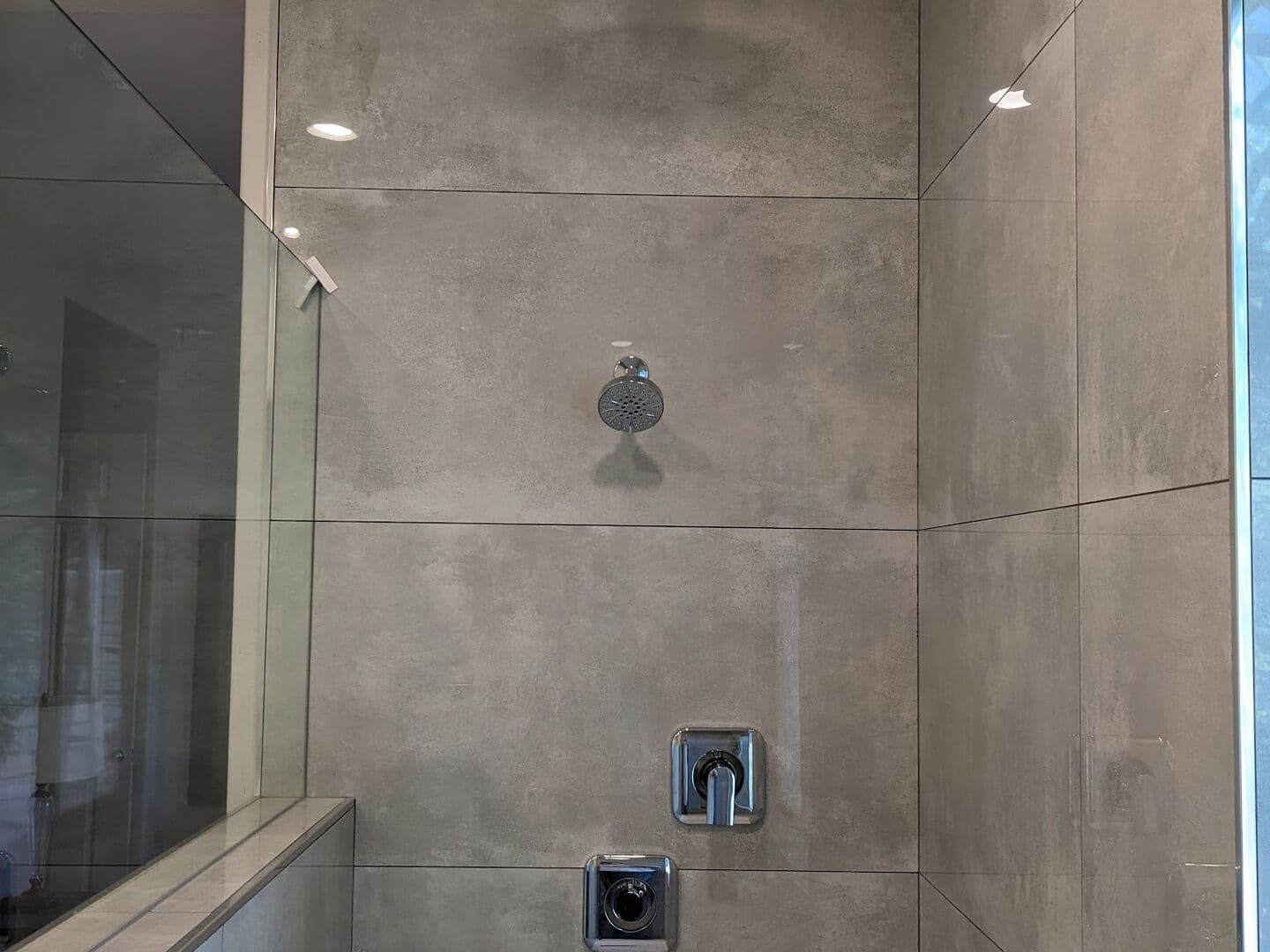 Large-format concrete-look porcelain shower with a frameless glass enclosure
