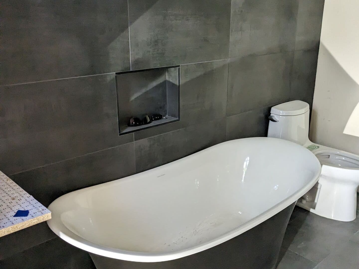 Bathroom in dark grey large-format porcelain with a freestanding tub and a wall niche