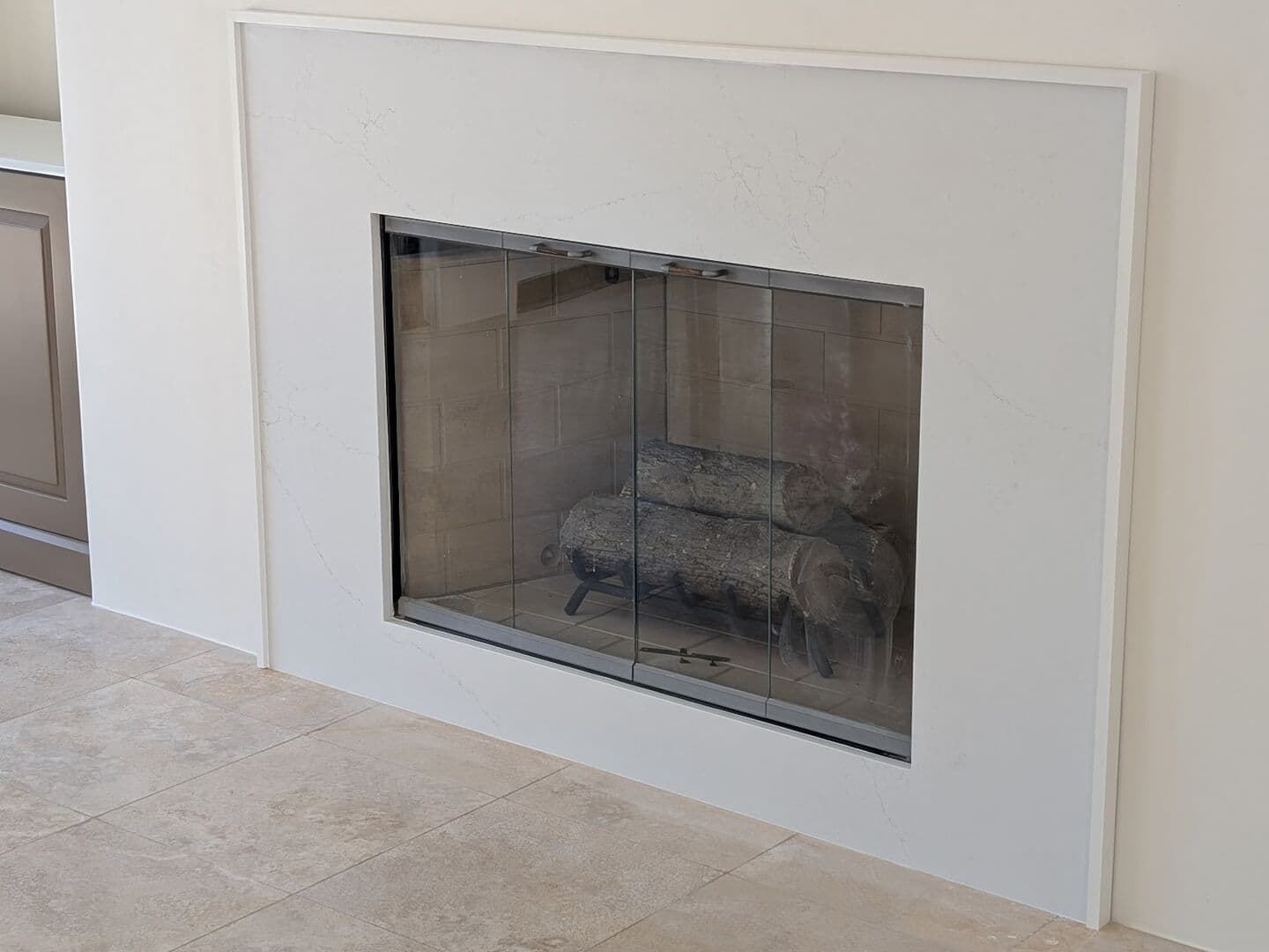 Before: flat white drywall fireplace surround over a travertine floor