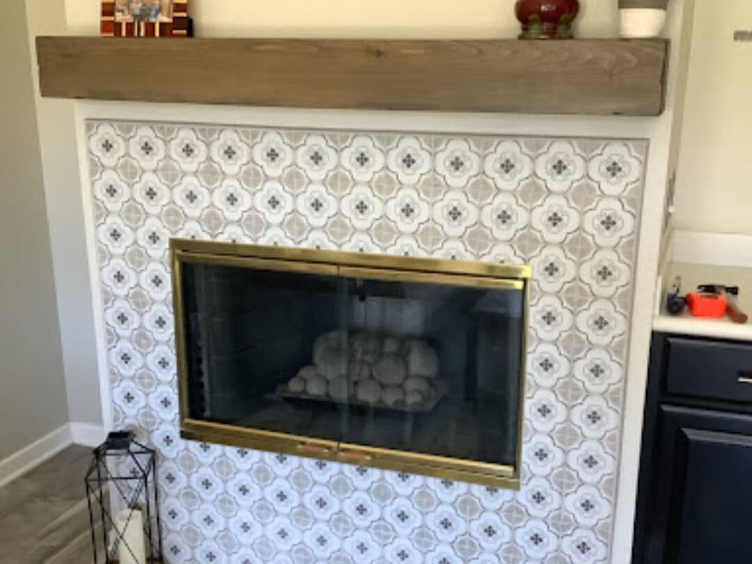 After: surround and hearth tiled in grey-and-white patterned porcelain under a wood mantel