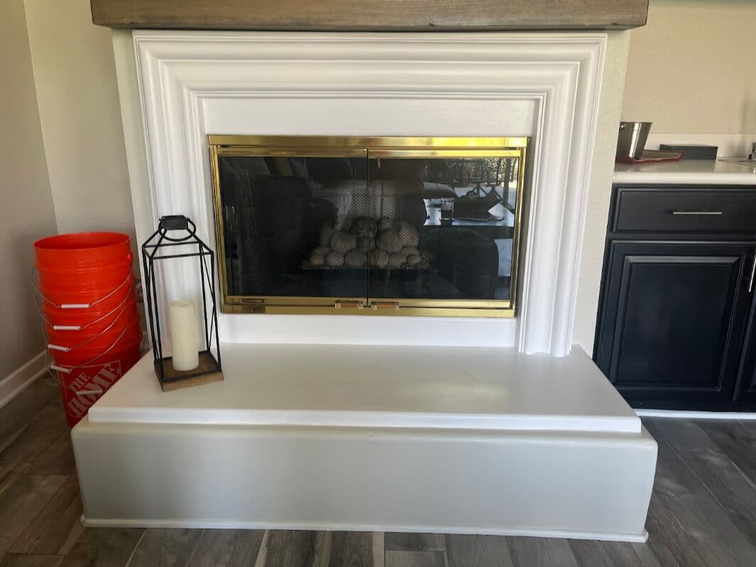 Before: white painted fireplace surround with a brass insert and a bare raised hearth