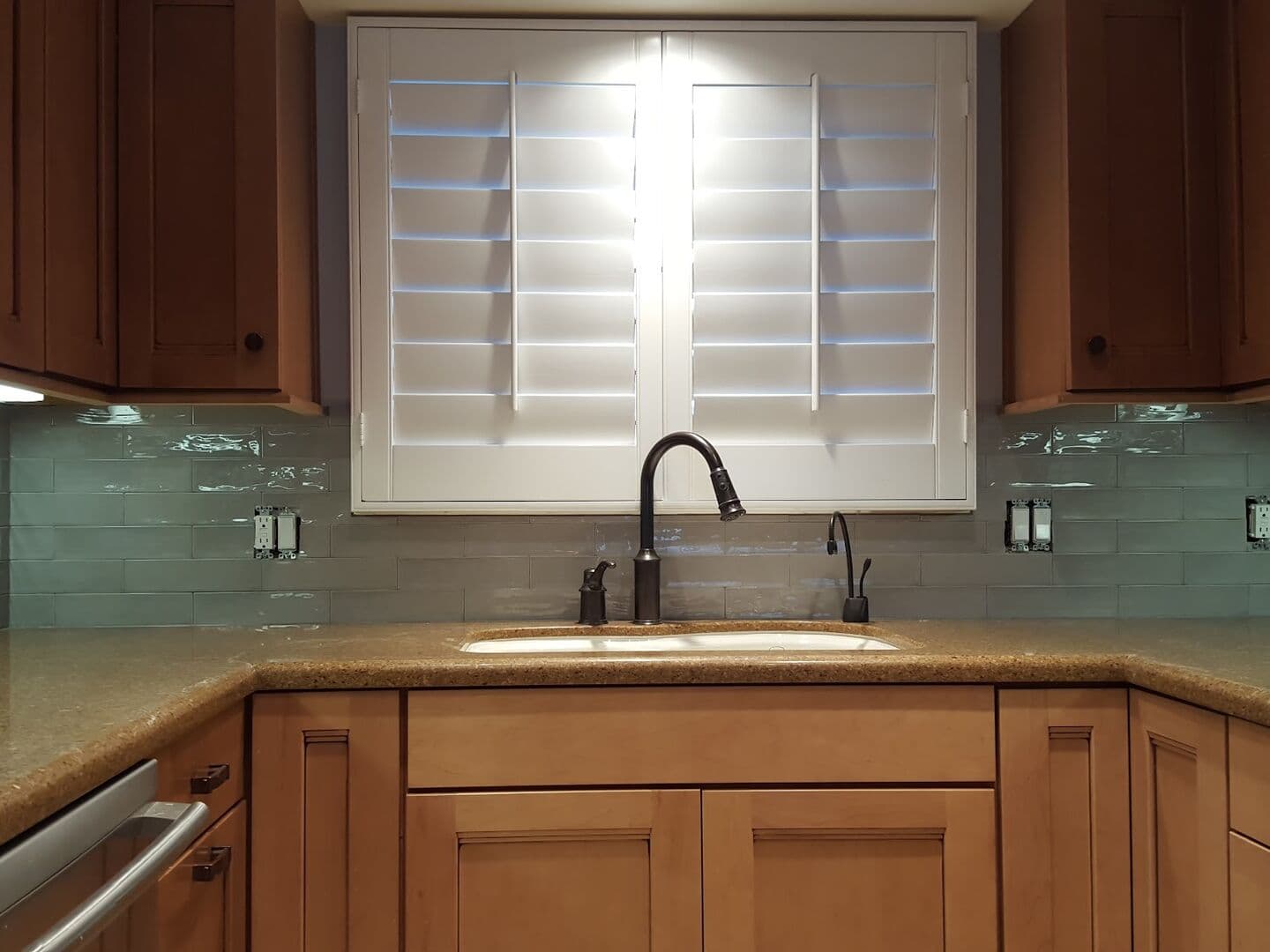 Kitchen with a glass subway tile backsplash under plantation shutters