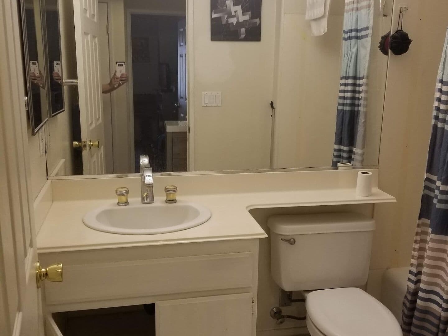 Before: dated hall bath with a cultured-marble vanity, brass hardware and a shower curtain