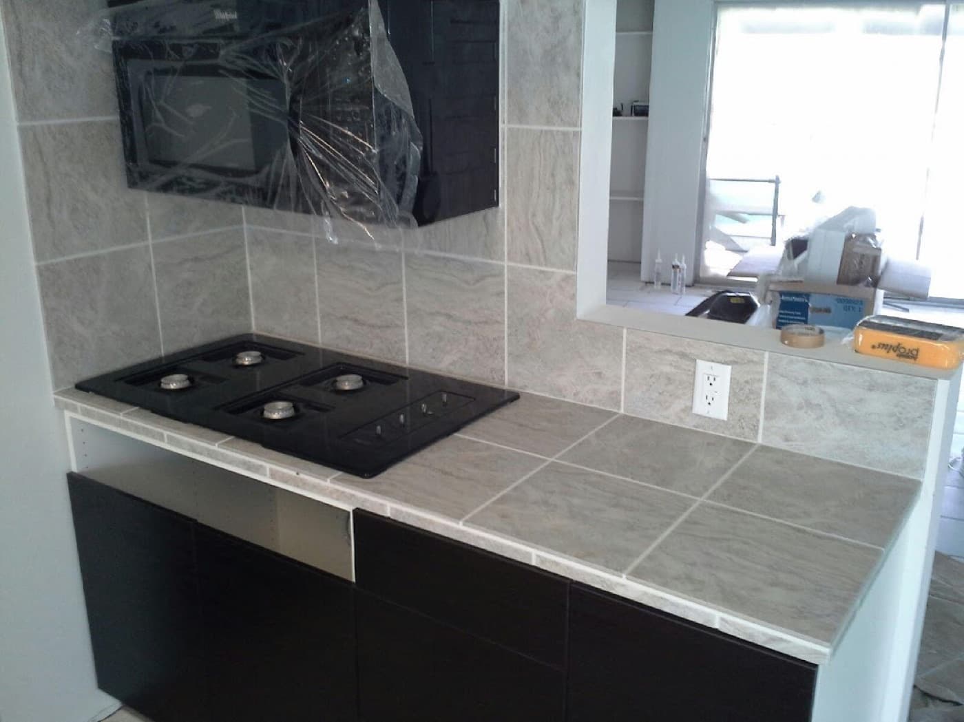 Stone-look porcelain tile countertop and backsplash set around a cooktop