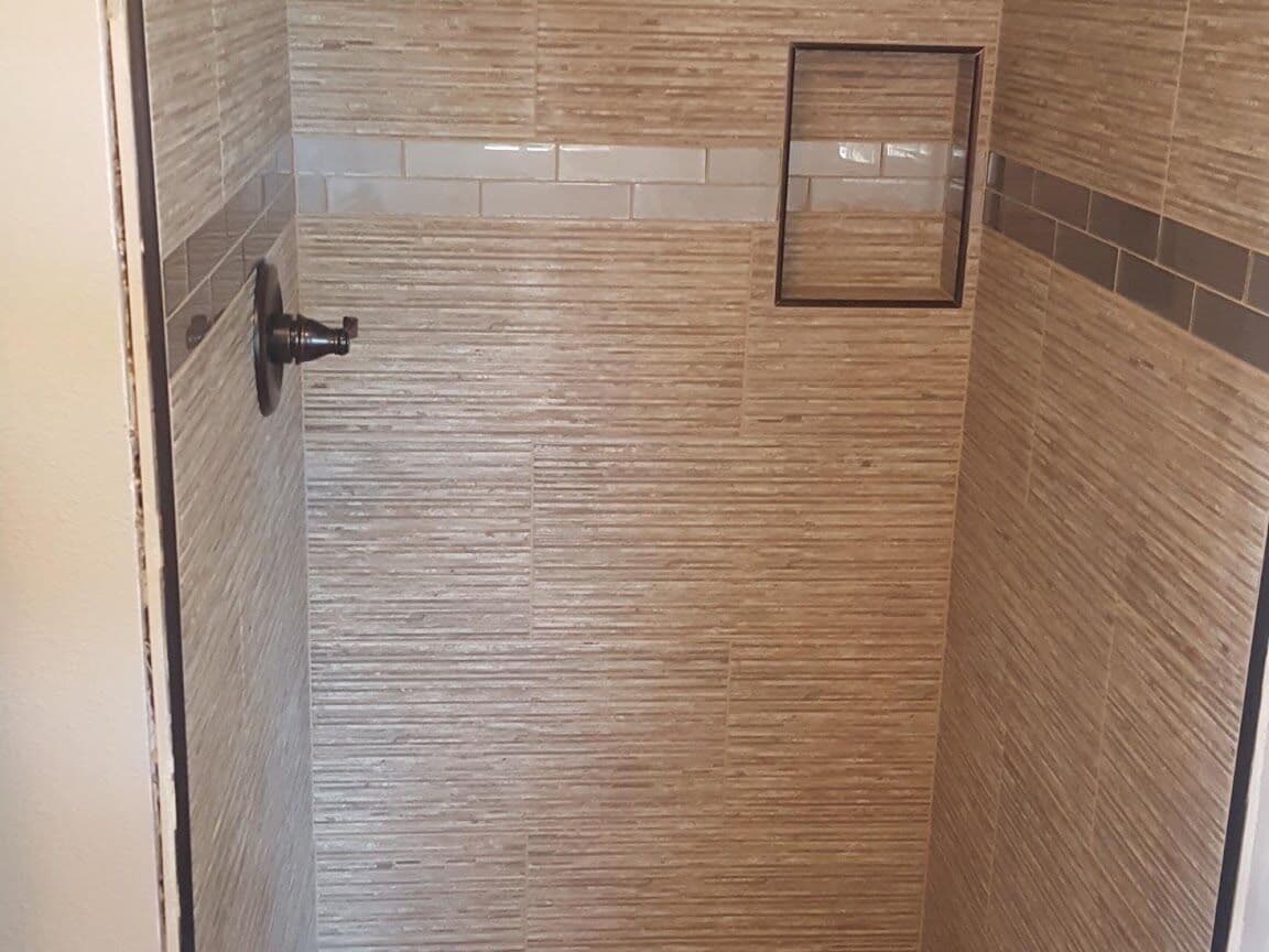 Walk-in shower in wood-look linear porcelain with a hexagon stone mosaic floor