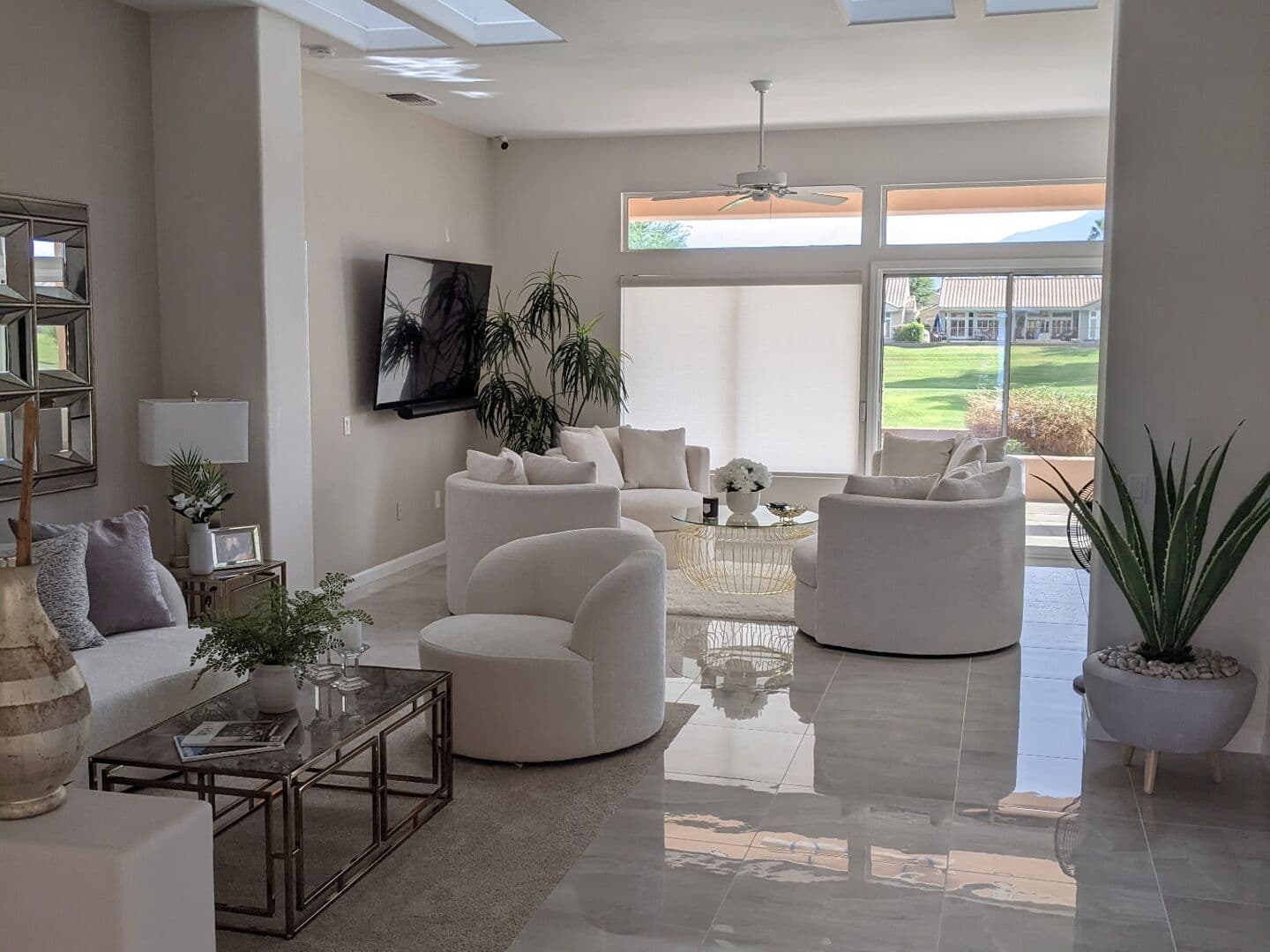 After: polished large-format porcelain floor running through the furnished living room under the skylights