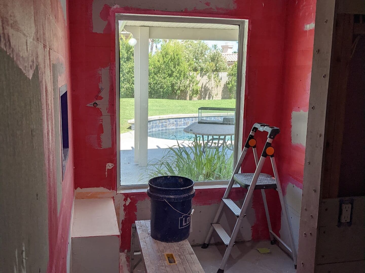 Before: the old shower gutted to the framing, with red waterproofing membrane going up around the window