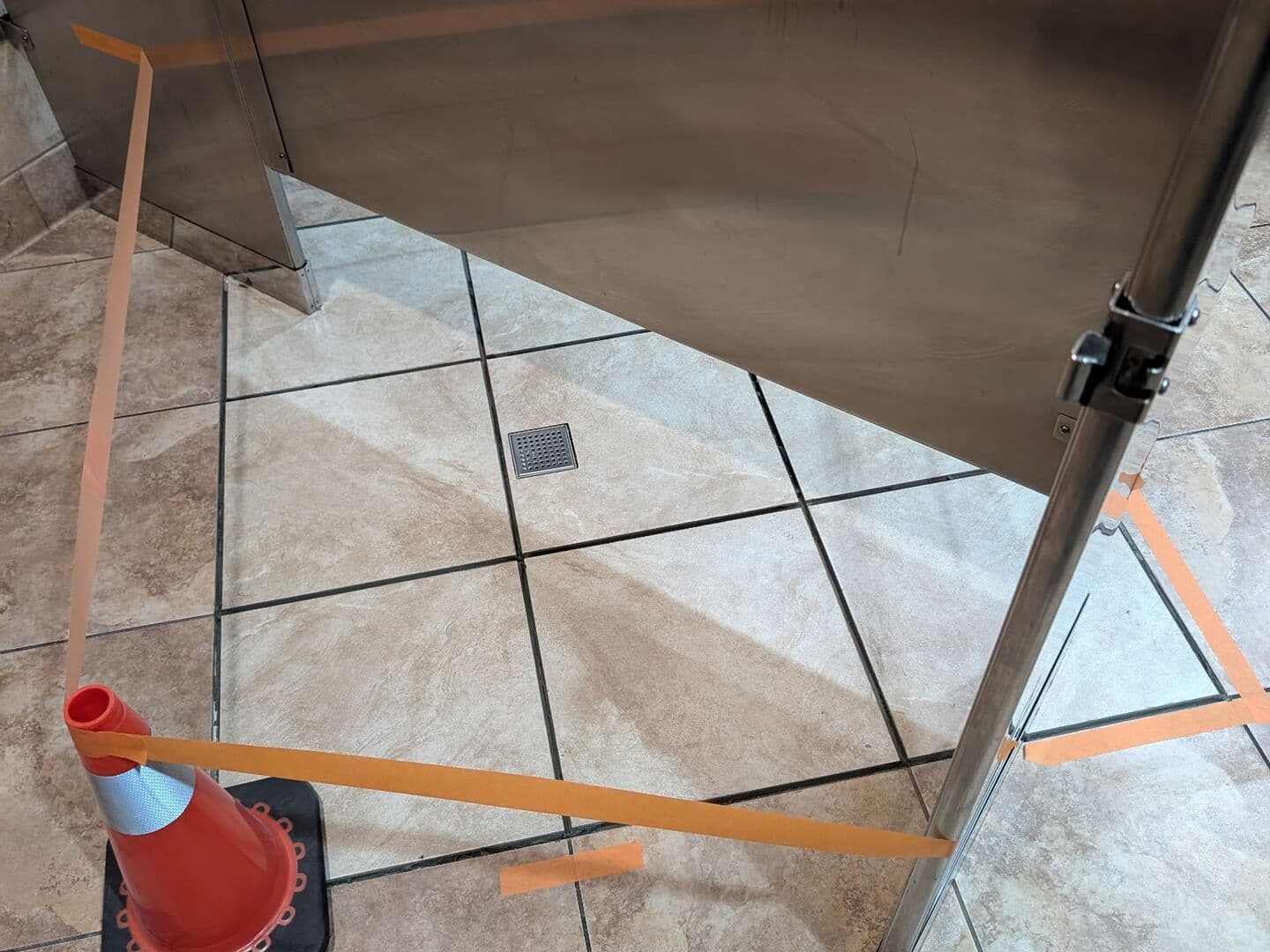 After: new tile set and grouted around the drain, matched to the existing floor under the stall partition
