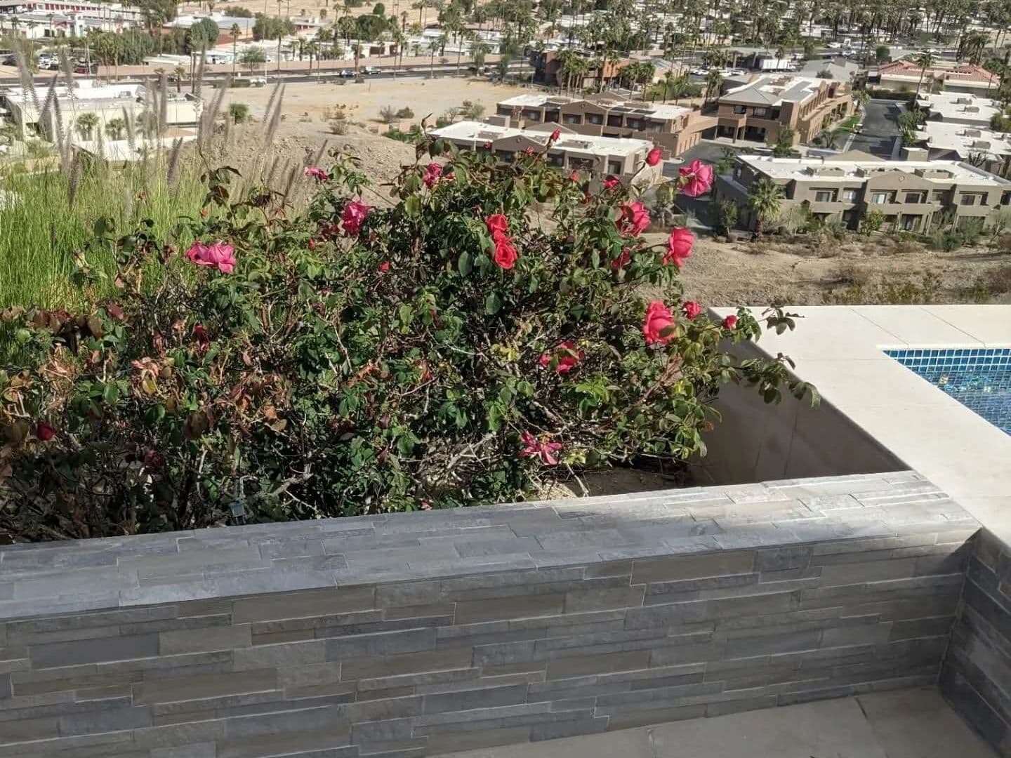 Stacked stone planter wall beside a pool with a valley view