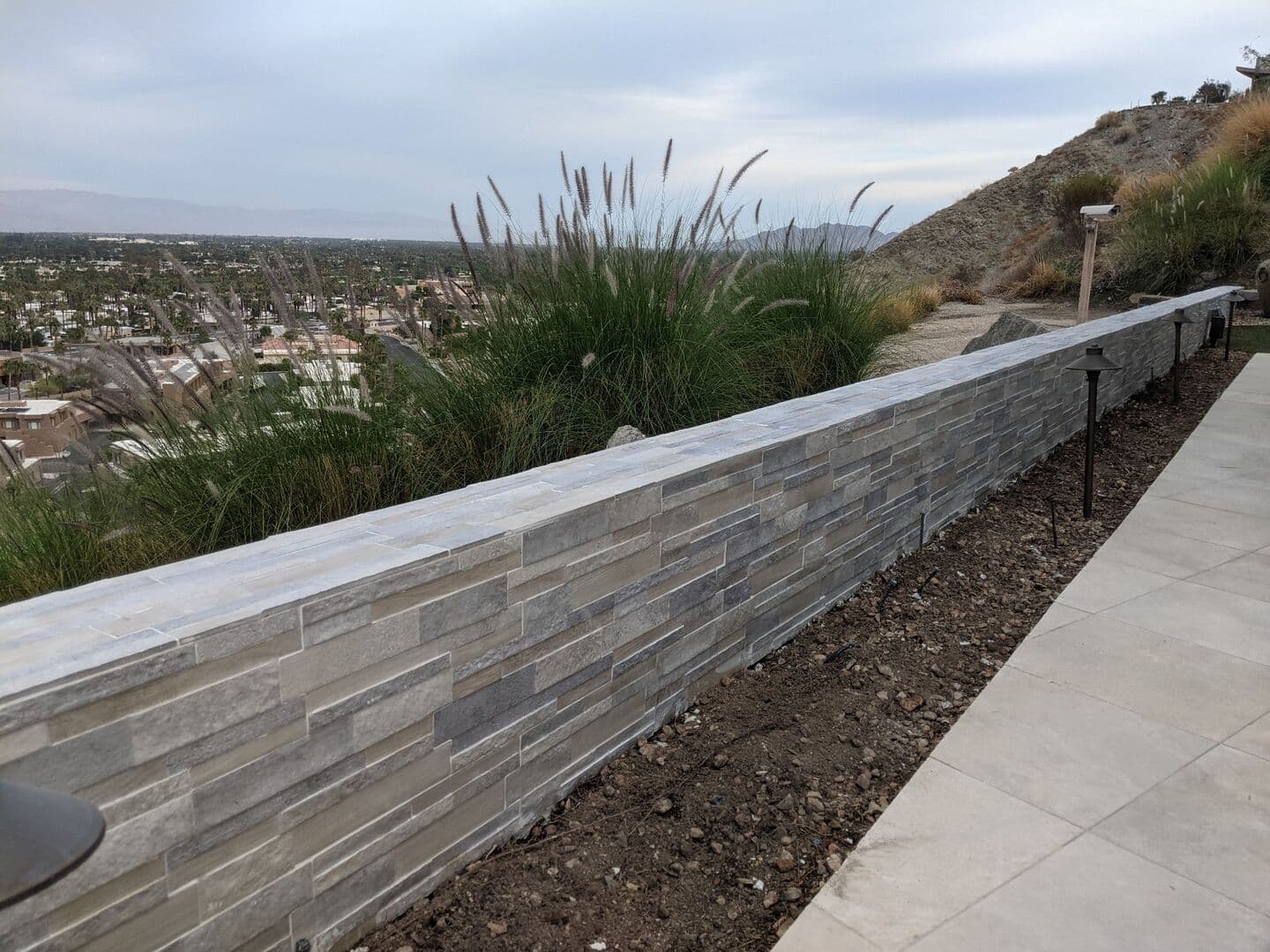 Stacked stone retaining wall along a patio with a valley view